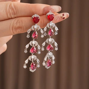 Close-up of luxury silver earrings with heart and pear-shaped red rubies and diamonds