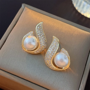 Close-up of pearl and zircon mermaid tail earrings in a brown leather jewelry box