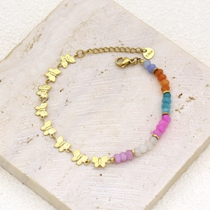 Detailed close-up of colorful faceted beads and a gold butterfly pendant on a steel bracelet