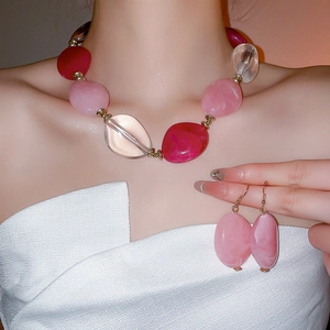 Detail of pink acrylic bead necklace and matching earrings on a model neck