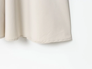Detail view of the fine hemline stitching on a beige belted dress fabric