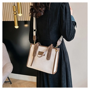 Detail of canvas tote bag with brown leather handles and adjustable shoulder strap