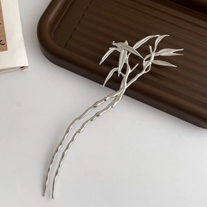 Detail of silver bamboo shaped hair pin with realistic metal leaves on a tray