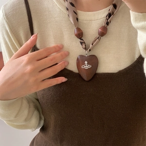Close-up of heart-shaped wooden pendant necklace with leopard print scarf chain