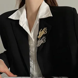 Polished gold and silver hand-shaped brooches set on a black suit lapel fashion accessory