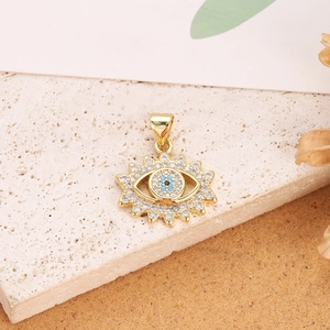 Macro shot of gold plated evil eye sunburst pendant with blue zircon stones on stone background