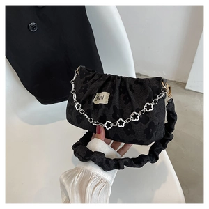 Detail of black fabric handbag with floral texture and silver flower chain strap