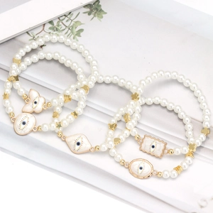Five-piece evil eye pearl bead bracelet set with gold heart and star charms on floral board