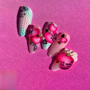 Detailed view of pink press-on nails with 3D hearts, pearls, and Chinese calligraphy art