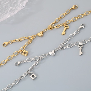 Close-up of magnetic heart pendants and key lock charms on gold and silver chain bracelets