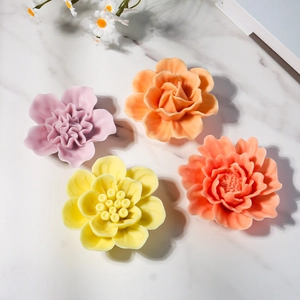 Detailweergave van vier kleurrijke 3D bloemkaarsen in roos- en pioenroosvorm op marmer
