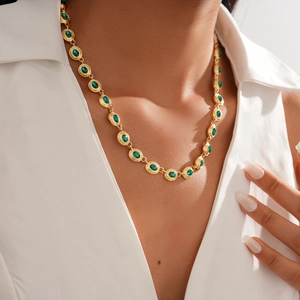 Close-up of vintage golden necklace with oval green gemstones on female model