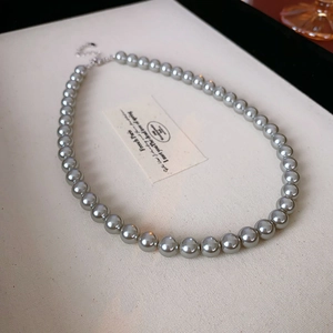 Detail einer grauen Perlenkette mit silbernem Karabinerverschluss und Kette