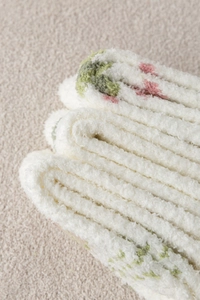 Macro shot of fluffy coral fleece socks with pastel tulip patterns and soft plush texture