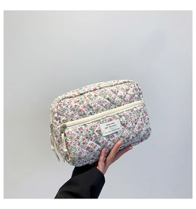 Detailed close-up of a quilted floral makeup bag in white cotton with a zipper closure