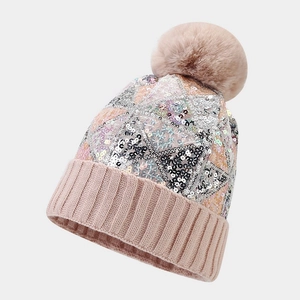 Detail of sequins and ribbed cuff on a warm knit winter beanie with fluffy pom-pom