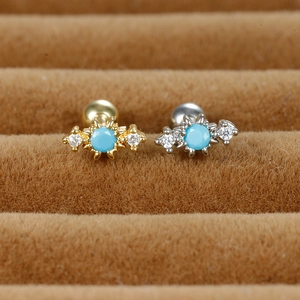 Macro detail of geometric earring with turquoise center and zircon studs on velvet