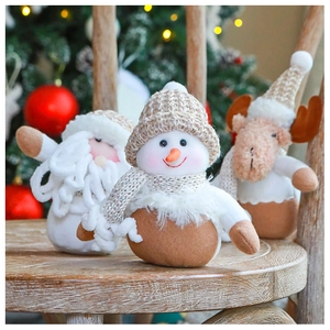 Detail of Christmas knitted snowman and reindeer dolls on wooden stool with warm lights