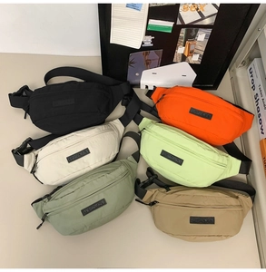 Flat lay of nylon crossbody bags in six vibrant colors with adjustable straps and buckles