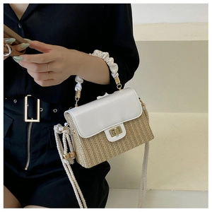Detail of straw woven box bag with white pleated handle and golden twist lock closure