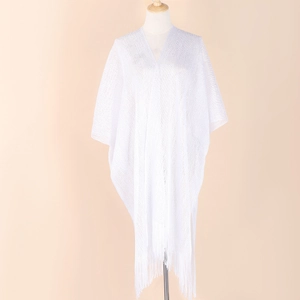 Detailed close-up of white knitted shawl with tassel hem and breathable fabric texture