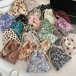 Macro view of assorted floral and pattern drawstring fabric storage pouches for cosmetics