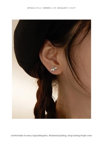 Detail view of 925 silver angel wing stud earring with gray gemstone worn on model