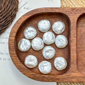 Close-up of irregular baroque white shell beads with pearl luster on a wooden tray