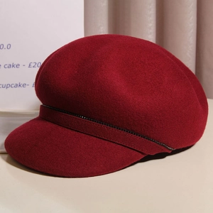 Detail of burgundy wool baker boy hat featuring a chic black beaded chain decorative strap