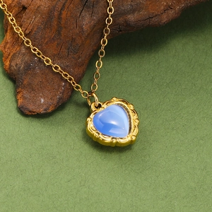 Détail du pendentif cœur en pierre œil-de-chat bleue avec bordure gravée dorée