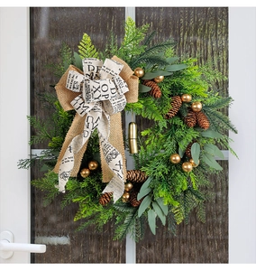 Close-up of Christmas wreath with pine cones and golden bells on a dark textured door