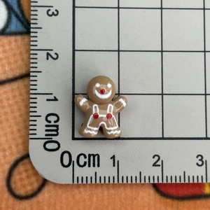 Macro shot of 1.7cm gingerbread man resin charm on a ruler showing exact size details