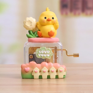 Hand-crank music box with a cute yellow chick and flower design in a pink-green finish