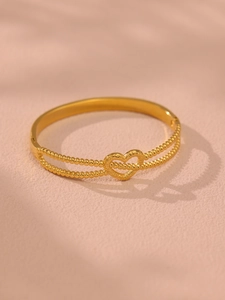Vue macro d'un bracelet en acier doré à double rangée de perles avec cœur évidé