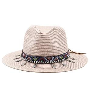 Détail d'un chapeau de paille bohème avec ruban ethnique et pendentifs en feuilles