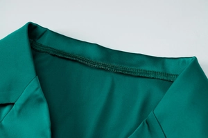 Détail du col d'une chemise en satin vert montrant les coutures et la texture du tissu soyeux