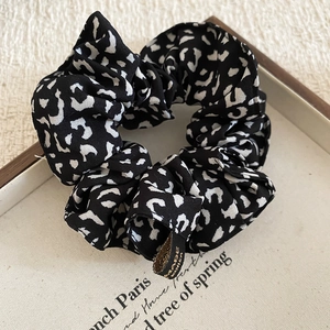 Detailed close-up of a leopard print fabric scrunchie with a hand made woven label tag