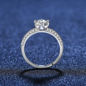Detail of a six-prong solitaire ring with pave set stones on a blue glitter surface