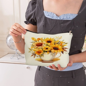 Waterproof linen makeup bag with sunflower print held by a hand for size reference