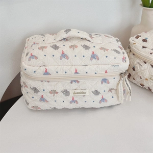 Close-up of beige quilted makeup bag with elephant print and sturdy carry handle