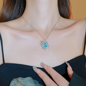 Detail of blue teardrop gemstone pendant with small pearls and crystals on silver chain