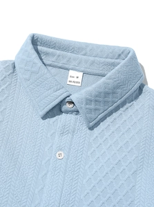 Close-up of light blue knit shirt collar with geometric texture and buttons