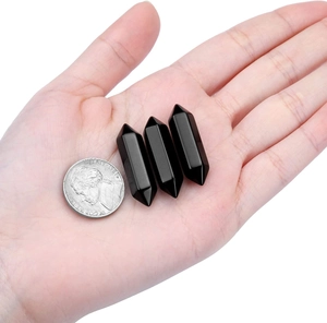 Three pieces of polished black hexagonal quartz pillars shown with a coin for size reference