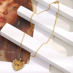 Detail der 18K vergoldeten Herzkette mit rotem Edelstein und Zirkon auf einer Perlenkette