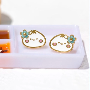Detail of cute cartoon dumpling earrings with white enamel finish and gold edges