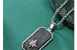 Detail of forged carbon fiber pendant with silver star icon on a steel chain necklace