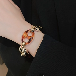 Dettaglio di un bracciale a maglie grosse con stampa leopardata e finitura dorata vintage