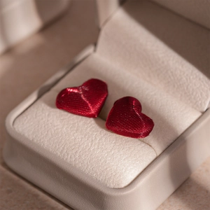 Detailed macro view of dark red heart earrings with textured silk thread wrap texture