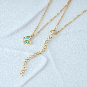 Macro detail of gold butterfly pendant necklace with turquoise stones on a white background