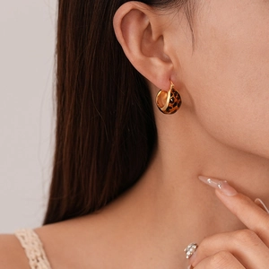 Close-up of elegant gold C-shape leopard print hoop earrings worn by a model